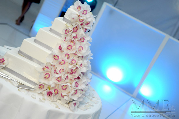 White wedding cake design with flowers framed by lighting backdrop